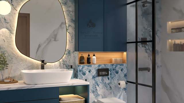 Three-quarter view of the vanity wall: warm halo glow around an organic brass-framed mirror, white vessel basin with matte-black mixer, teal cabinetry and an oak-lined niche of amber and black toiletries beside a gridded black shower screen.
