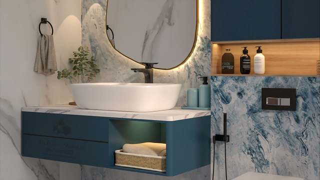Close-up of a floating teal vanity with white-marble top and rounded vessel basin, matte-black tap and ring towel holder, a woven towel basket in the lit open shelf and a glowing oak niche set into swirling blue marble.