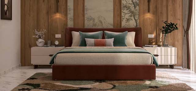 Closer view of the burgundy velvet bed dressed in oatmeal linen, sage velvet cushions and a terracotta-striped bolster, flanked by fluted ivory nightstands with brass clock and blossom vase, warm wall-washer sconces on oak planks behind.