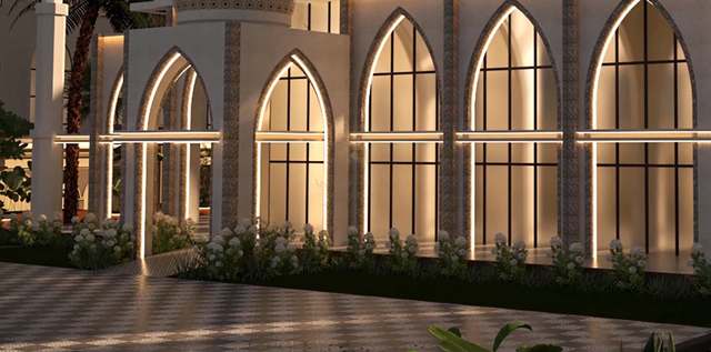 Night detail of the mosque arcade: pointed arches outlined in warm LED strips, glowing amber glazing with black mullions, mosaic pilasters and a bed of white hydrangeas above a softly lit checkerboard plaza.